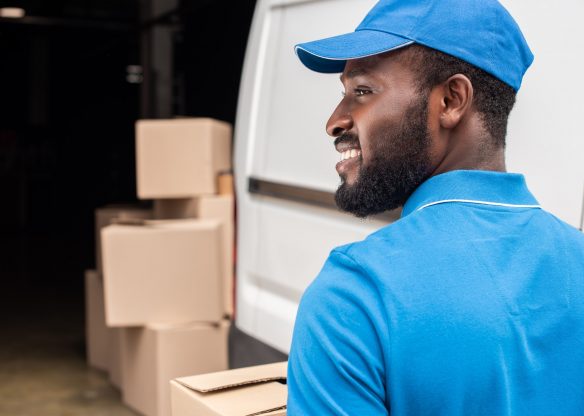 side view of smiling african american delivery man looking away